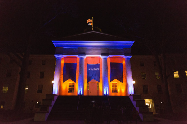 Penn Hall lit up in orange and blue for Twilight Hour.
